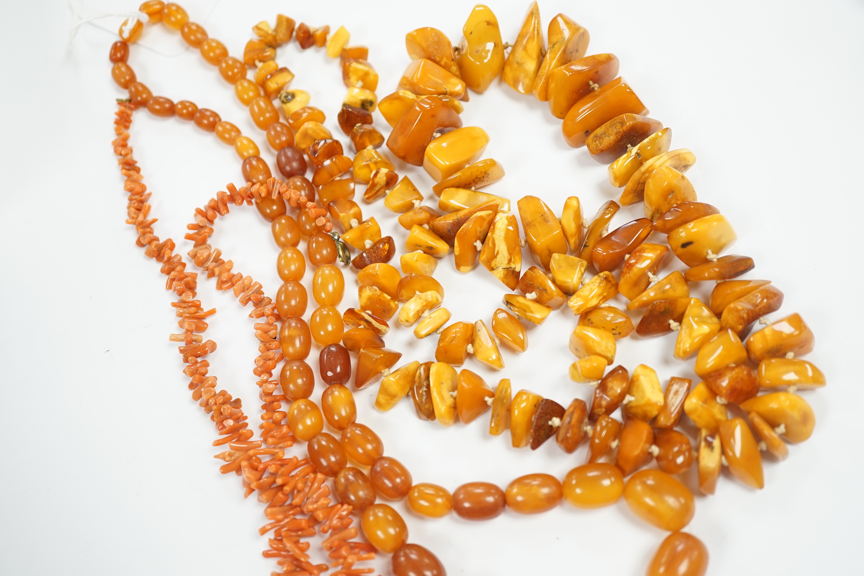 A single strand graduated amber bead necklace, 56cm, gross weight 34 grams, one other amber necklace and a coral necklace.